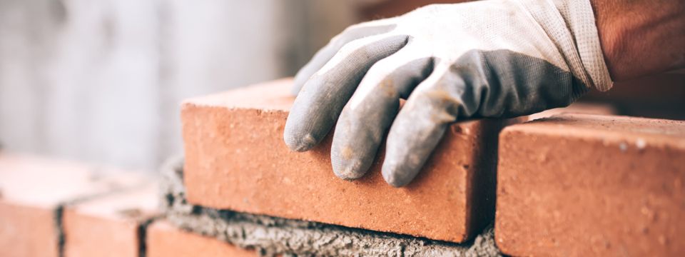 Close up of industrial bricklayer installing bricks on construction site