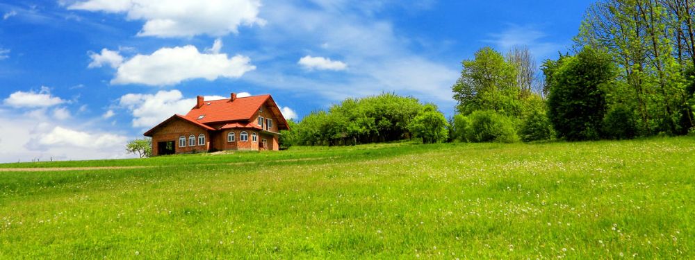 a house in green field with blue clear sky